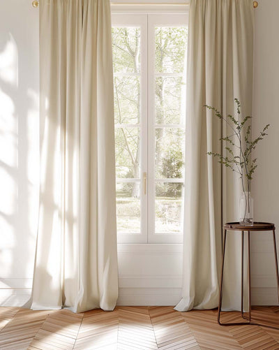 Cream coloured cotton curtains covering a window looking into garden