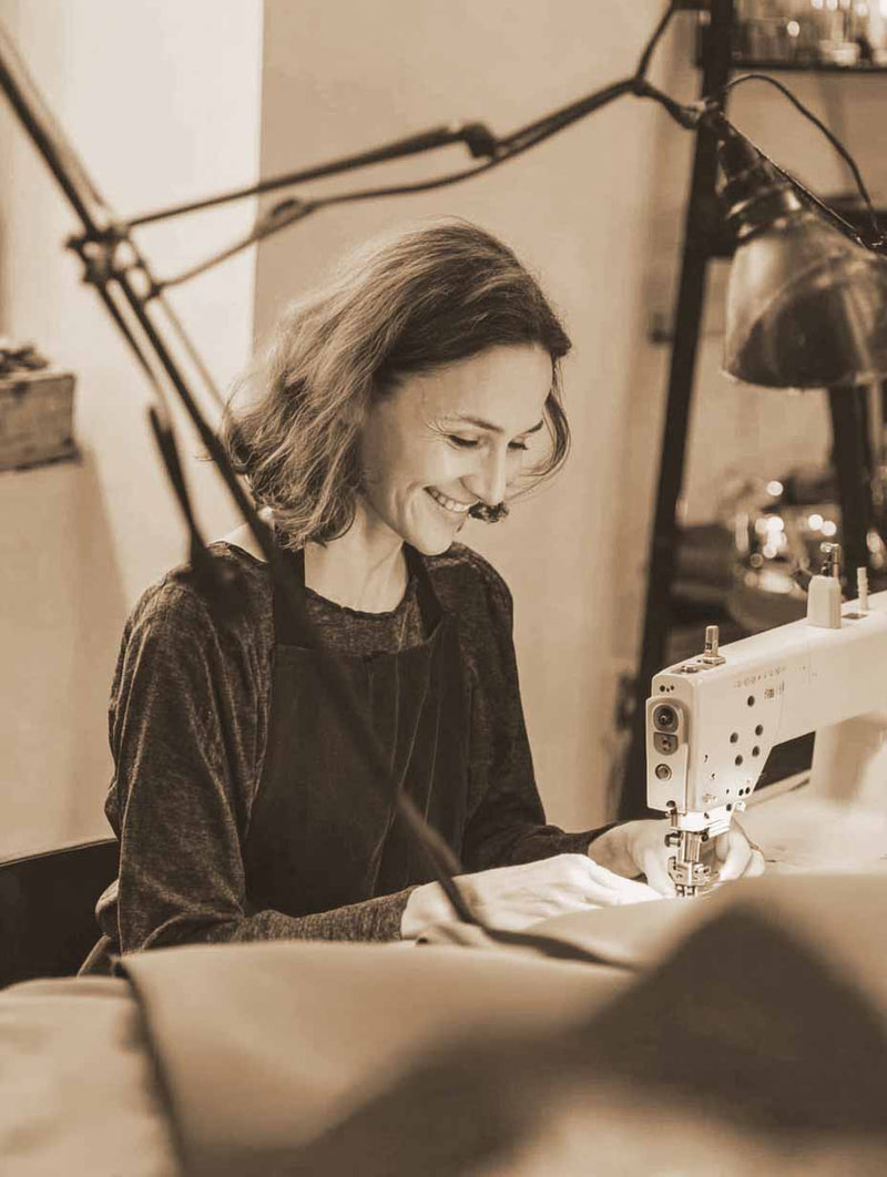 A women making made to measure roman blinds of natural linen fabric with lining in sewing studio UK