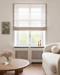 A light beige linen Roman blind with horizontal pleats.