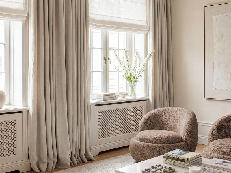Living room with tall light bespoke beige linen curtains with blackout lining with  upholstered linen fabric armchair